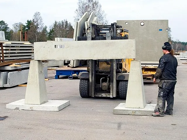 Man i arbetskläder framför betongbalkar