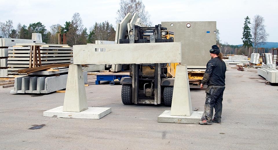 Man i arbetskläder framför betongbalkar